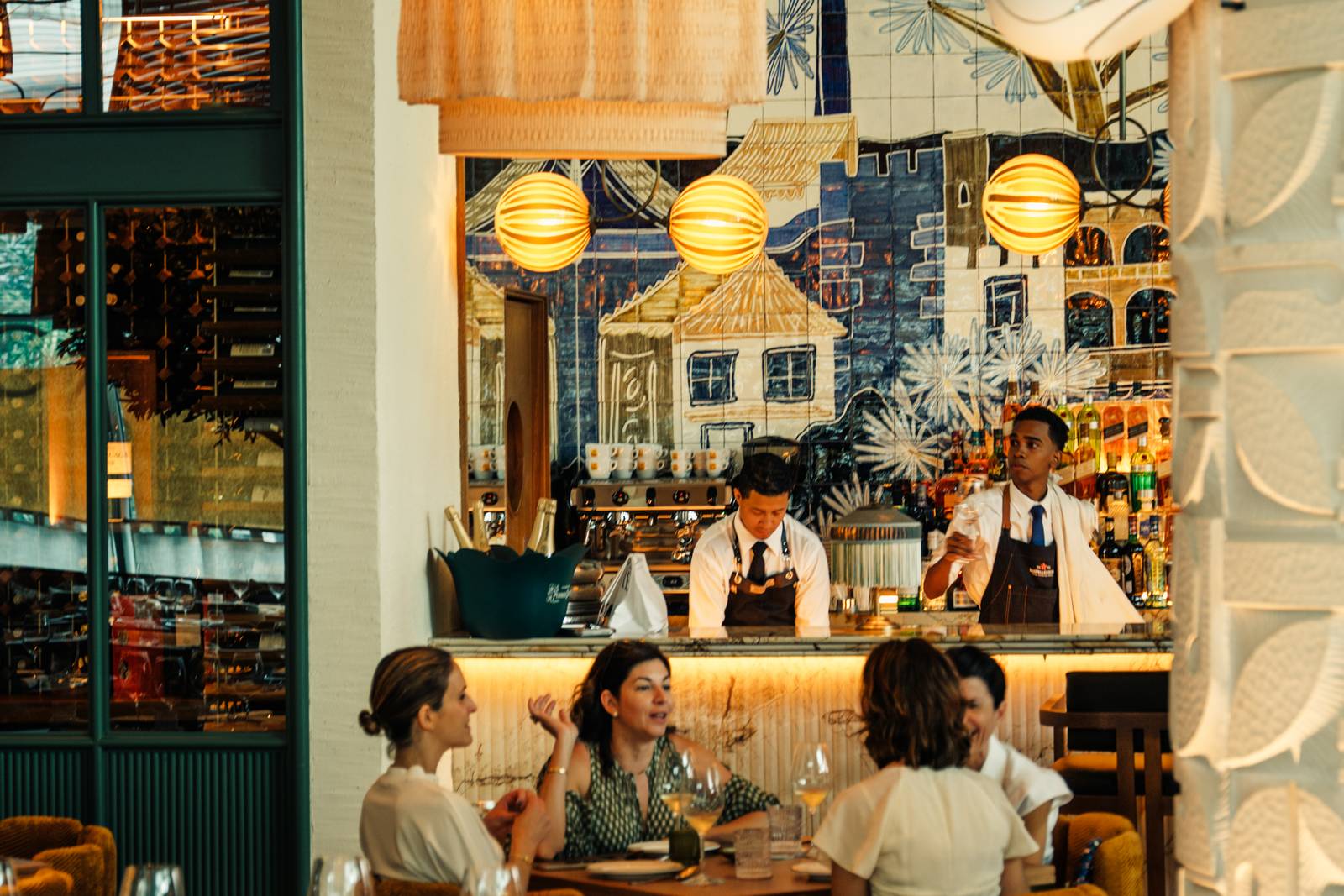 Barra del restaurante con bartenders y la cava de vinos al fondo