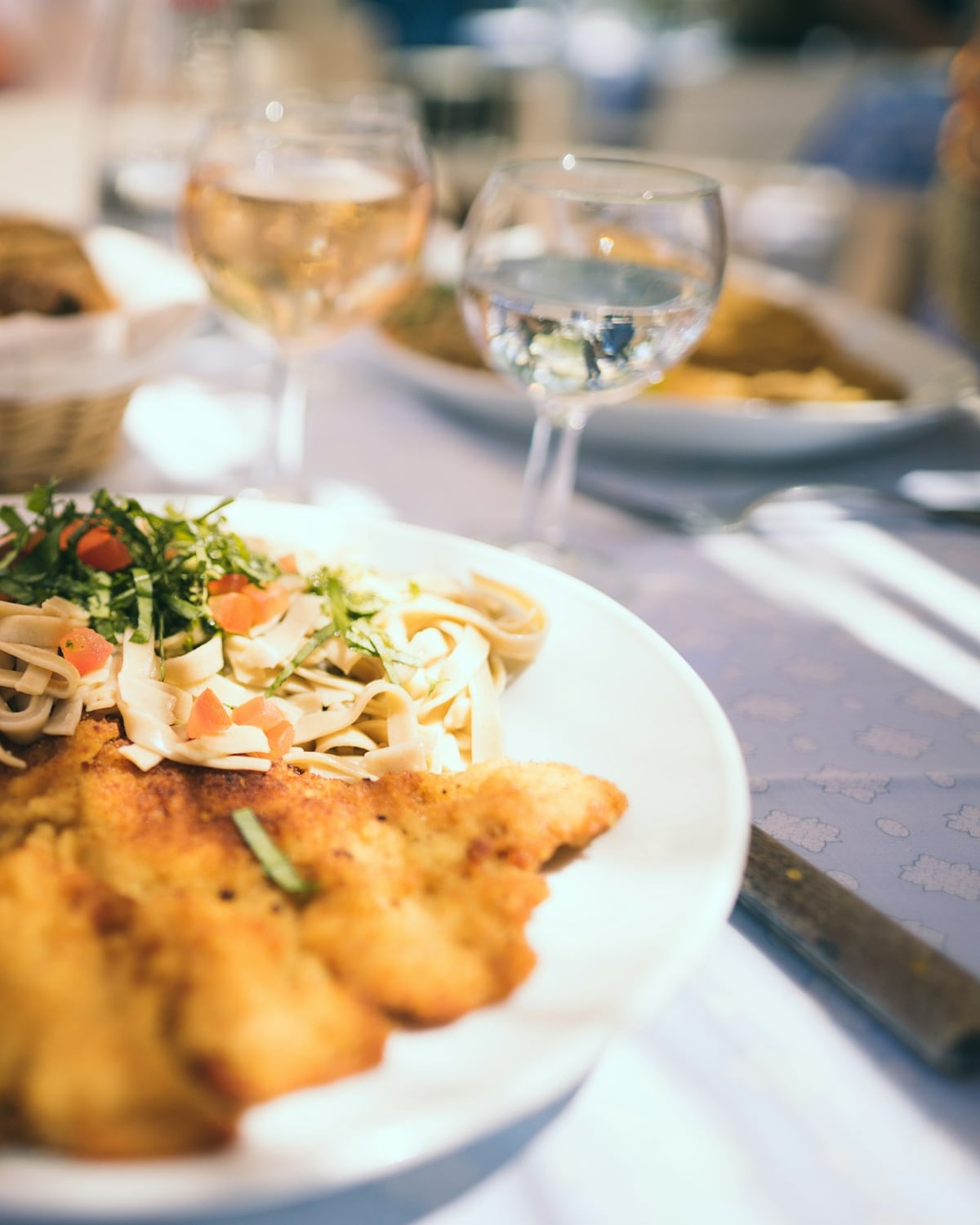 Milanesa empanizada con ensalada sobre un plato blanco en la mesa de un restaurante