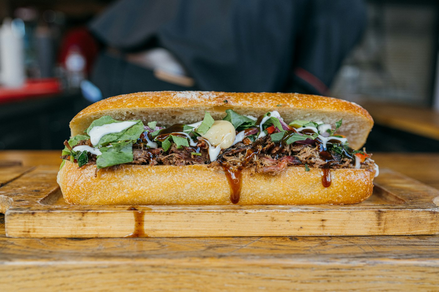 Sándwich de carne en pan crujiente sobre una tabla de madera