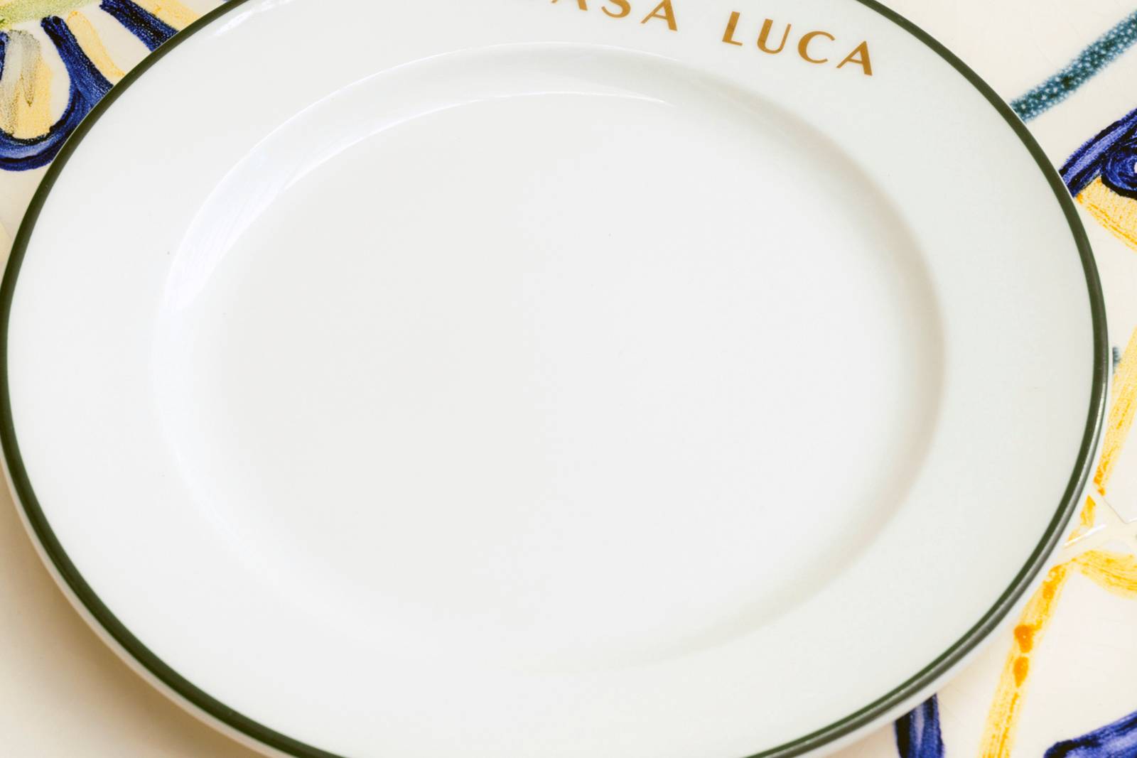 Plato blanco con el nombre Casa Luca y un borde de azulejo azul
